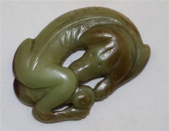 A Chinese greenish-yellow and brown jade carving of a recumbent hound, possibly Ming dynasty, 6.7cm